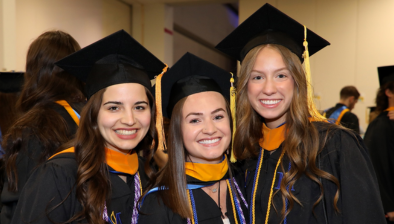 three students smiling the suburban showplace, waiting to walk out 和 be seated