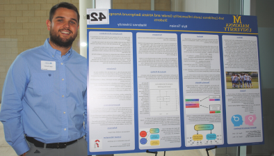 Kyle Tinnion smiling next to his re搜索 board at the 2023 Re搜索 Symposium